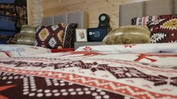 A bedroom with a bed covered in patterned bedding, a clock on the wall, and a framed picture above the bed.