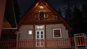 A wooden cabin with a balcony and a small porch.