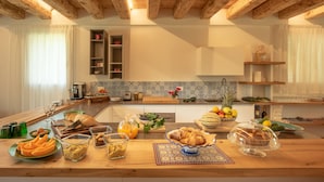 Una cocina con vigas de madera, salpicadero de azulejos y diversos alimentos para el desayuno sobre la encimera.