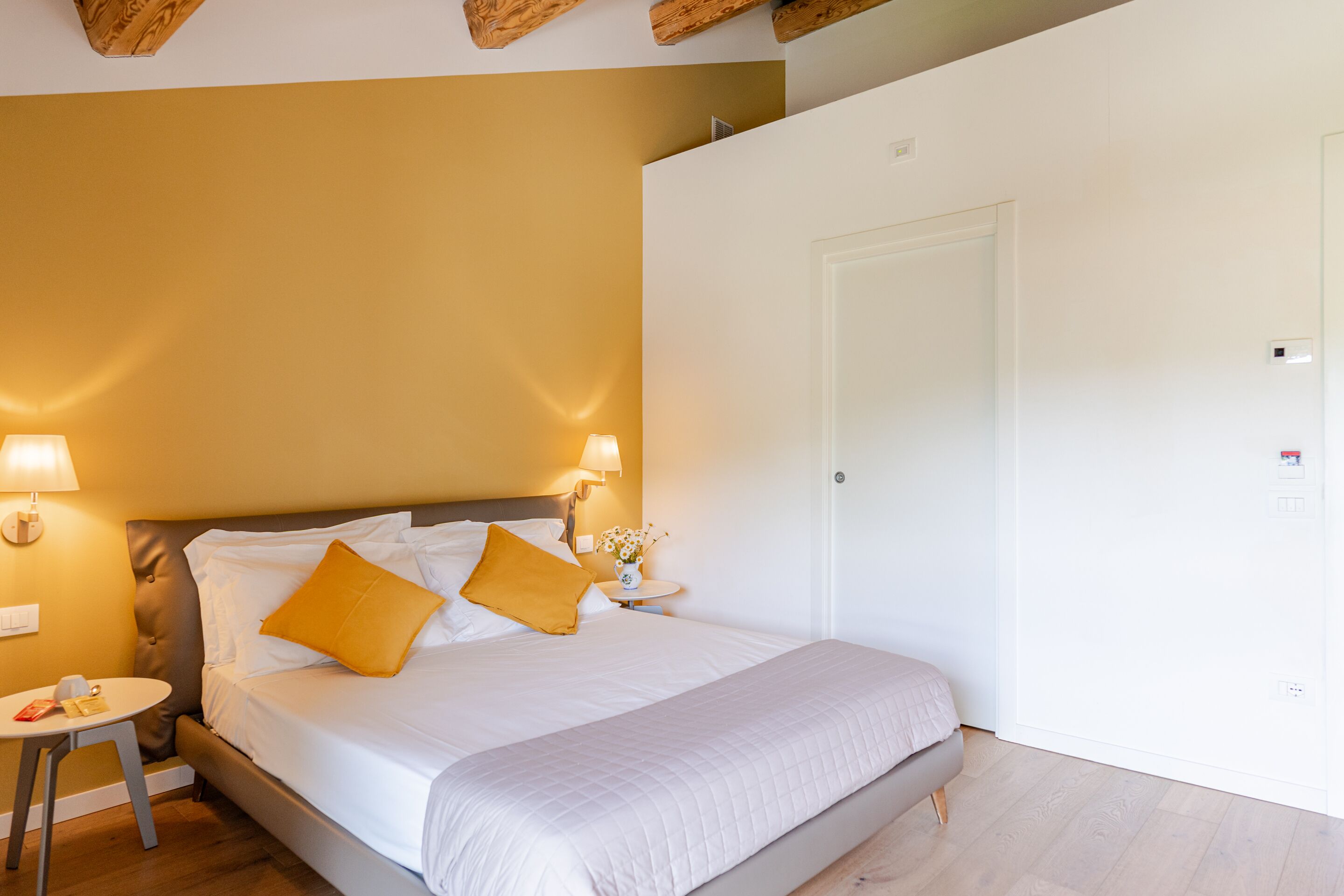 Ein Schlafzimmer mit einem Bett, Nachttischlampen, einem kleinen Tisch und einer weißen Tür.