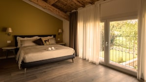 Un dormitorio con una cama grande, vigas de techo de madera, un balcón con vistas a zonas verdes y dos lámparas de noche.