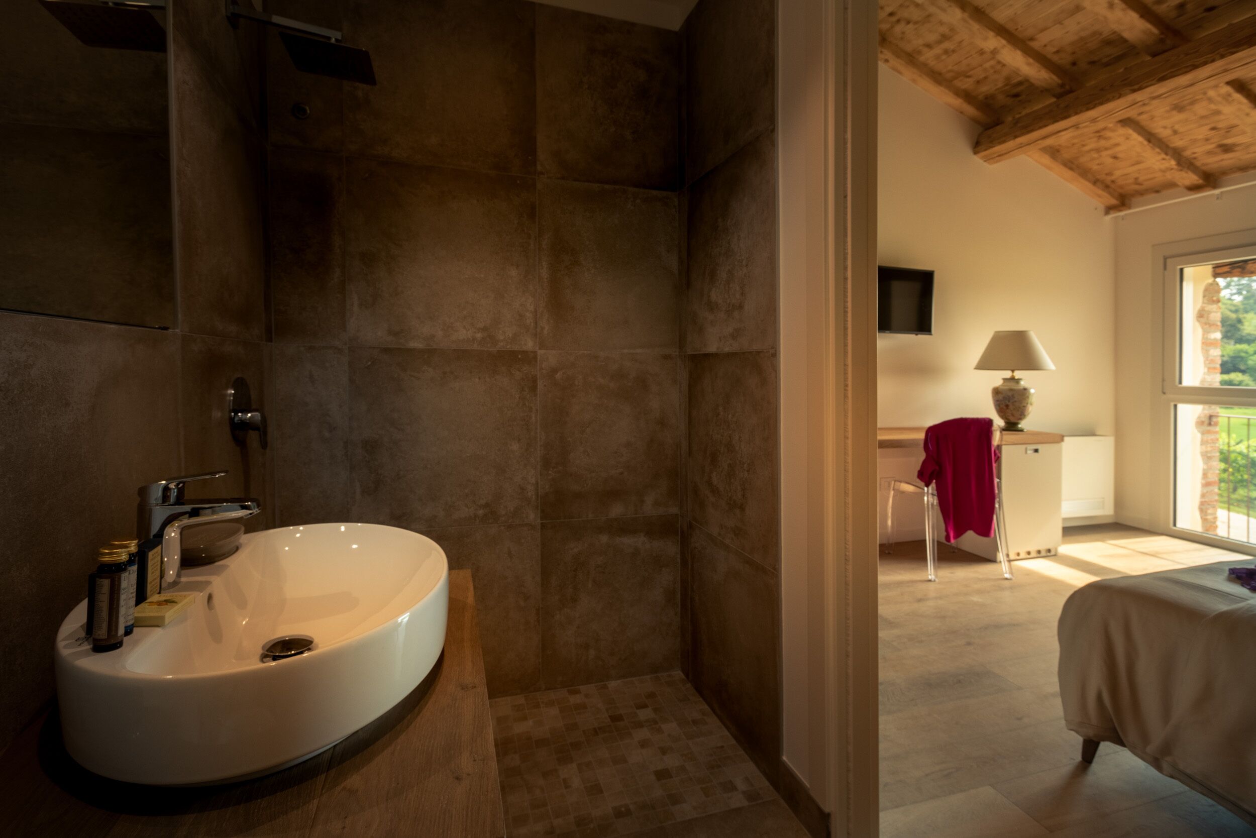 A bathroom with a large white sink, a shower, and a wooden ceiling.