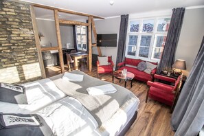 Een hotelkamer met een groot bed, een rode bank, een kleine tafel en een televisie.