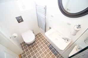 Een kleine badkamer met toilet, wastafel en douche.