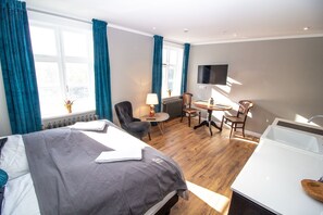 Een hotelkamer met een bed, een bureau, een stoel, een televisie en een bad.
