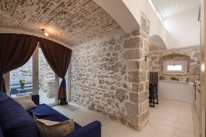 A cozy living room with a stone wall, a sofa, and a view of the outdoors.