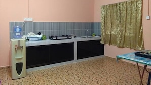 A compact kitchen with a water dispenser, a sink, and a small table with a tray. - Homestay Haji Ismail 5 bedrooms 2 Aircond (Kota Bharu)