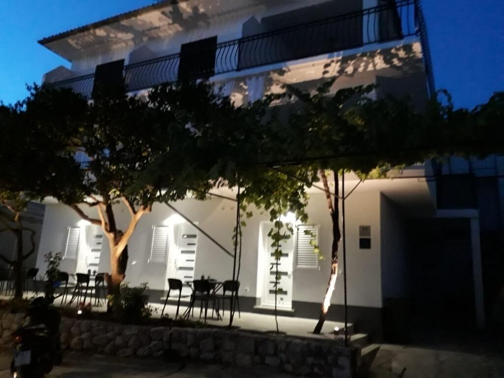 Ein Gebäude mit Balkon, Sitzgelegenheiten im Freien und einer Steinmauer.