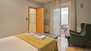 Een hotelkamer met een bed, een bankje, een stoel, een tafel en uitzicht naar buiten.