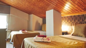 Hotellihuone, jossa on puinen katto, kaksi sänkyä, ikkuna ja seinä, jossa on geometrinen kuvio.
