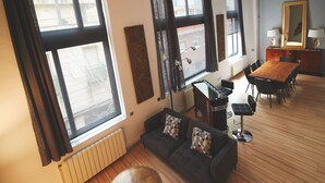 A modern living room with a sofa, a coffee table, and a dining area with a wooden table and chairs. - Alcam Alio Cine (Barcelona)