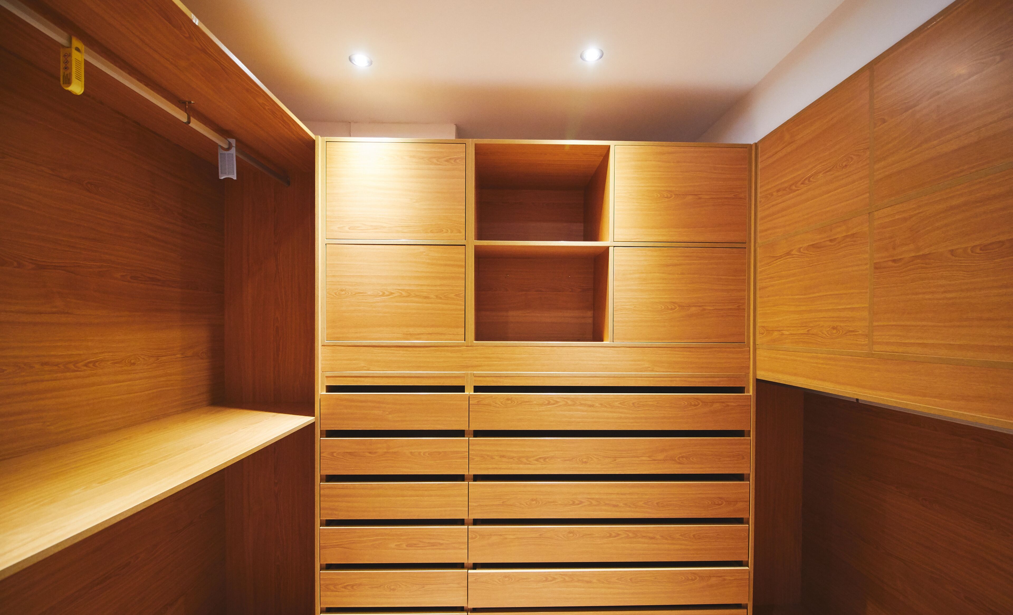 A wooden closet with multiple shelves and drawers.