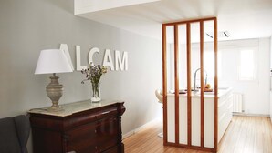 A modern kitchen with a wooden cabinet, a vase with flowers, and a large 'ALCAM' sign on the wall. - Alcam Alio Cine (Barcelona)