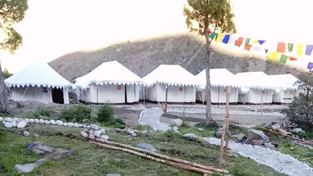 Una fila de tiendas blancas con un paisaje rocoso al fondo.