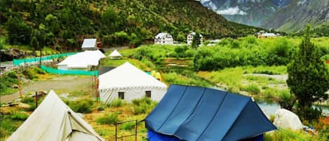 A mountainous landscape with several tents and buildings, suggesting a campsite or lodge.