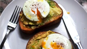Deux tranches de pain grillé garnies d’avocat et d’œufs pochés, présentées sur une assiette.