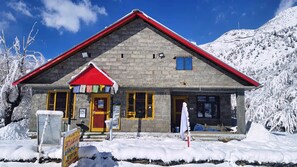 A stone building with a red roof and yellow windows, surrounded by snow.