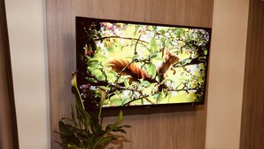 A television mounted on a wall with a potted plant beside it.