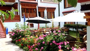 A courtyard with a seating area, a flag, and a building with traditional wooden balconies. - TIH Namra Village Hotel - Temisgam (Leh)