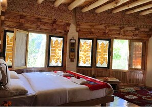 Une pièce en bois avec un lit, des fenêtres dotées de cadres décoratifs et un tapis rouge.