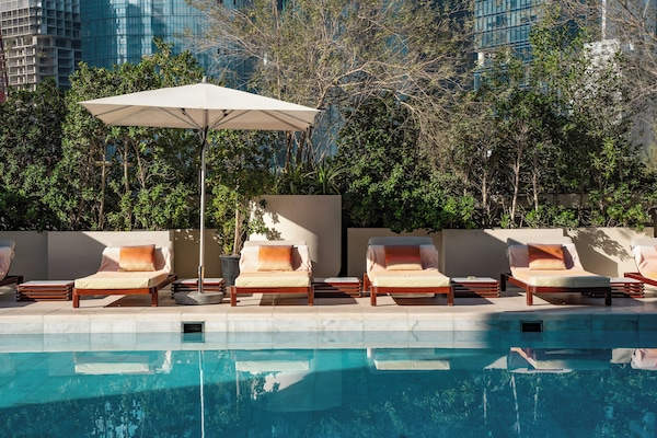 Een buitenzwembad, parasols bij het zwembad en ligstoelen