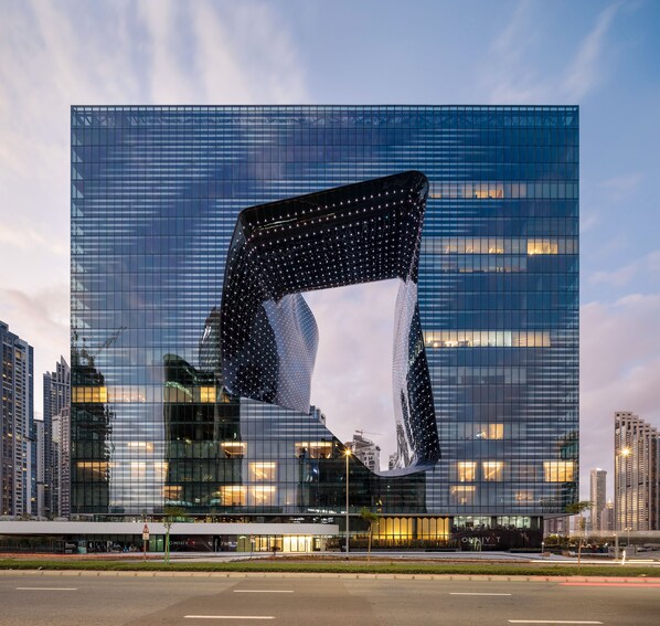 A modern glass building with a unique, curved facade. - ME Dubai by MeliĆ” (Dubai)