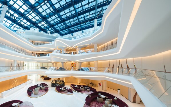 A modern, multi-level atrium with a glass ceiling, seating areas, and a central open space. - ME Dubai by Meliá (Dubai)