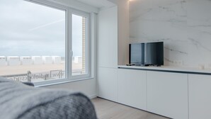 A modern kitchen with white cabinets, a marble backsplash, and a large window. - State-of-the-art studio with frontal sea view (Koksijde-Bad)