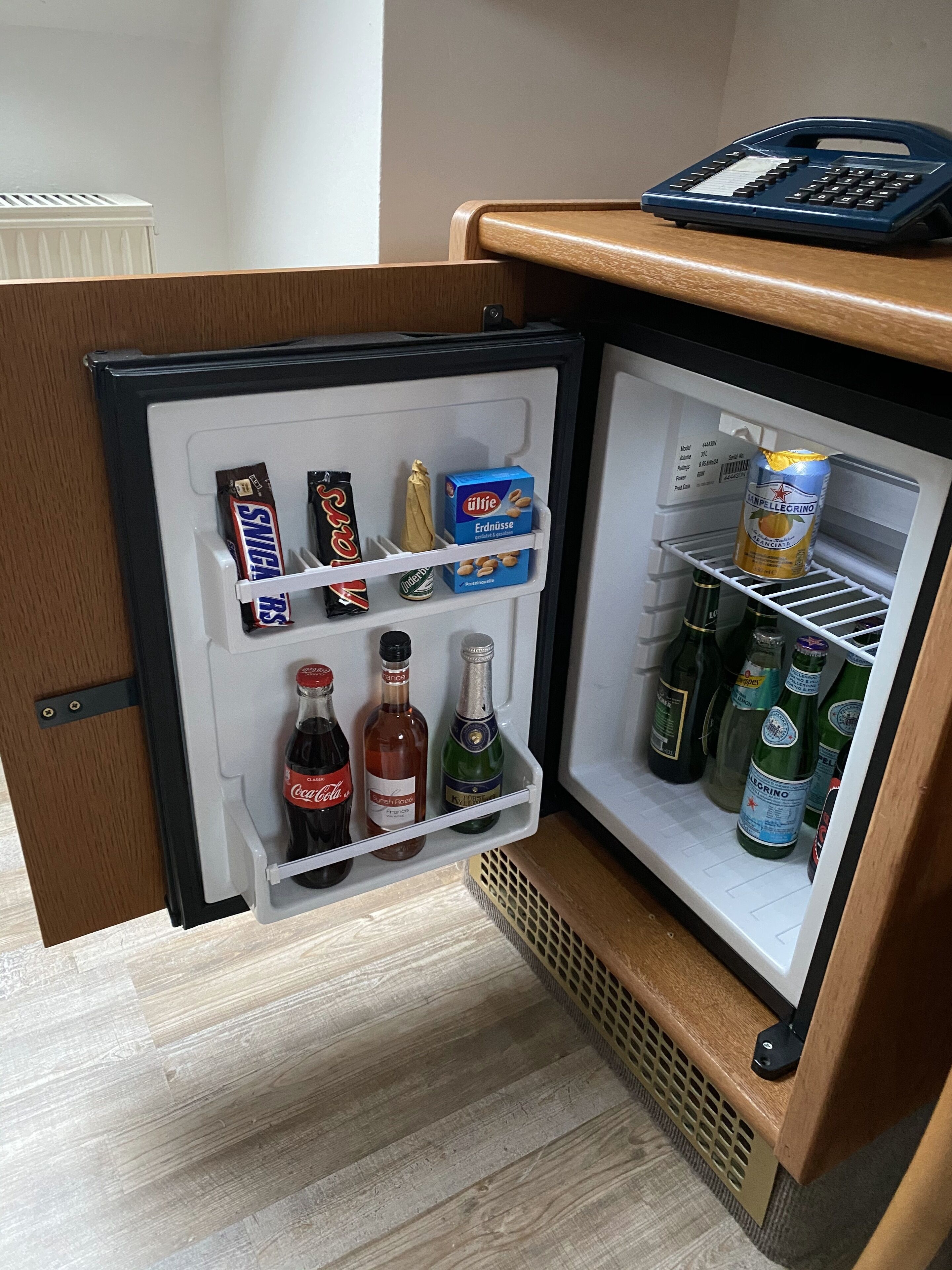 A compact refrigerator with a small freezer compartment, containing various food items, beverages, and a can of beer.