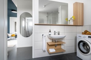 A modern bathroom with a sink, mirror, and washing machine. - BodenseeApartments (Friedrichshafen)