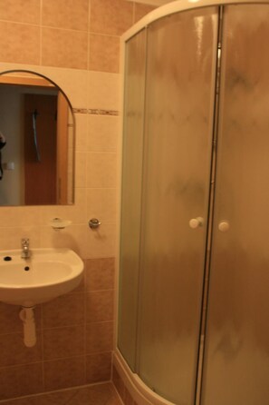 Un baño con lavamanos, espejo y ducha con mampara de vidrio.