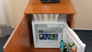 Ein kleiner Kühlschrank mit einem Fernseher darauf, gefüllt mit Getränken und Snacks.