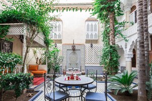 Un patio con una mesa redonda, sillas, un sofá y una fuente.