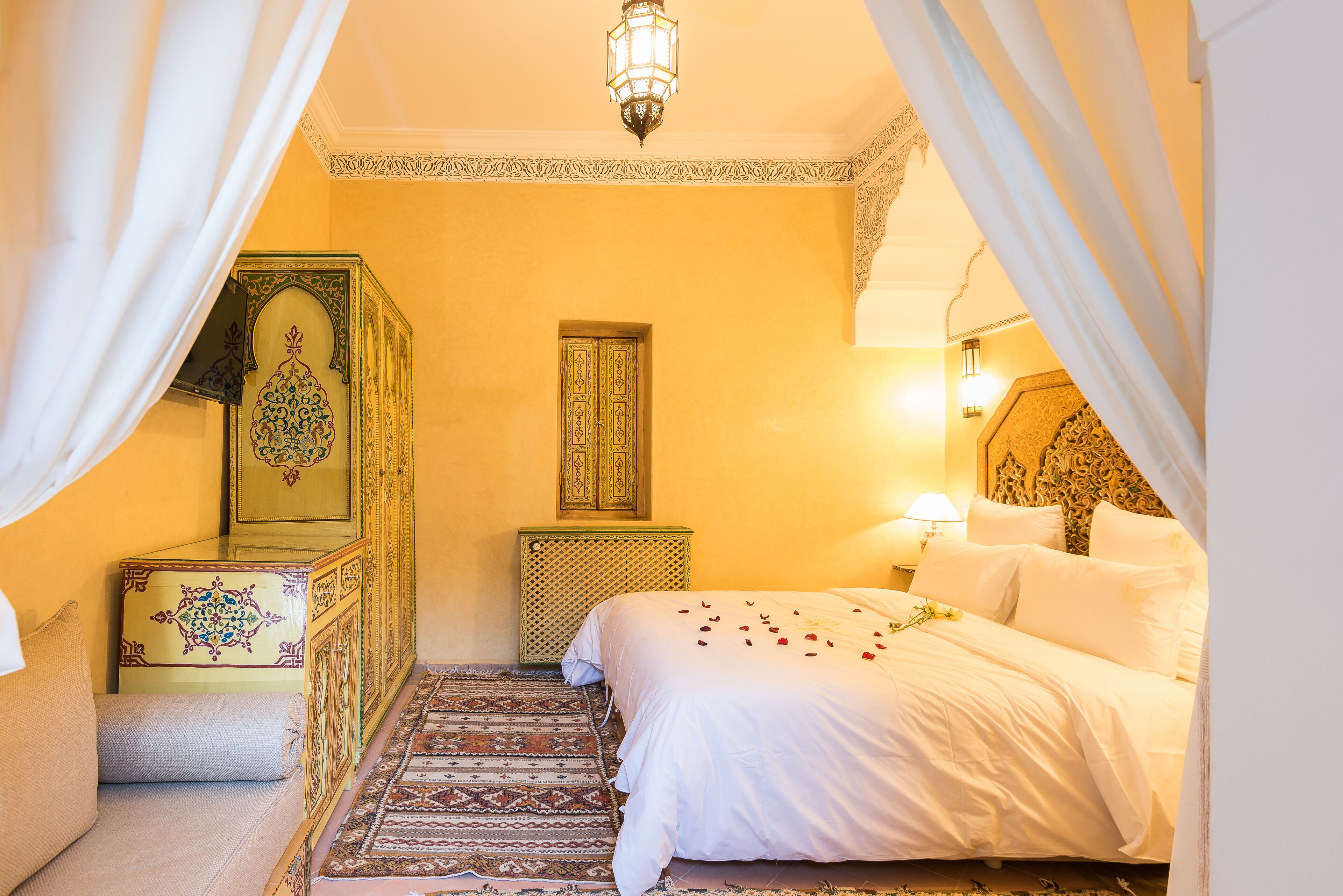Una camera tradizionale marocchina con un letto, un mobile decorativo e un tappeto ornamentato.