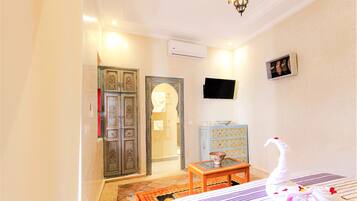 A hotel room with a bed, a small table, a TV, and a wardrobe.