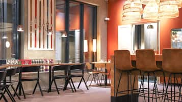 En moderne restaurant med en lang disk, sorte stole og et stort vindue med pynt i ski-tema.