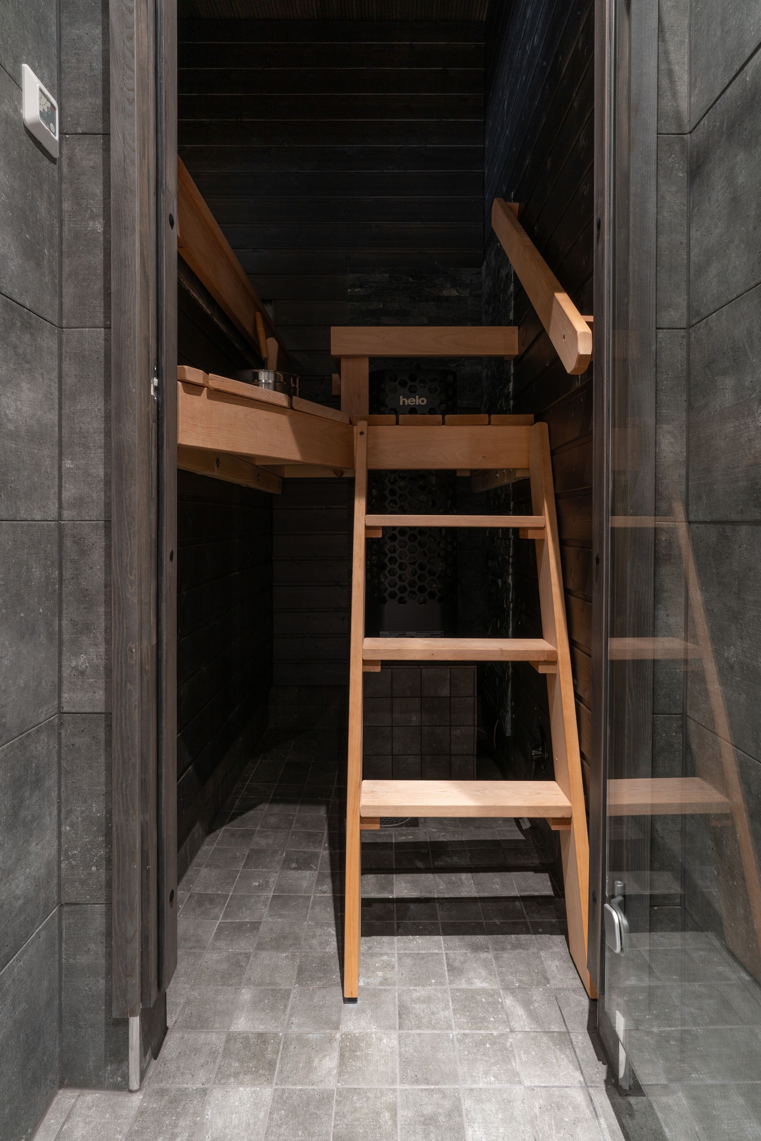 Una stanza compatta con una scala in legno, un piccolo ripiano e un pavimento piastrellato.