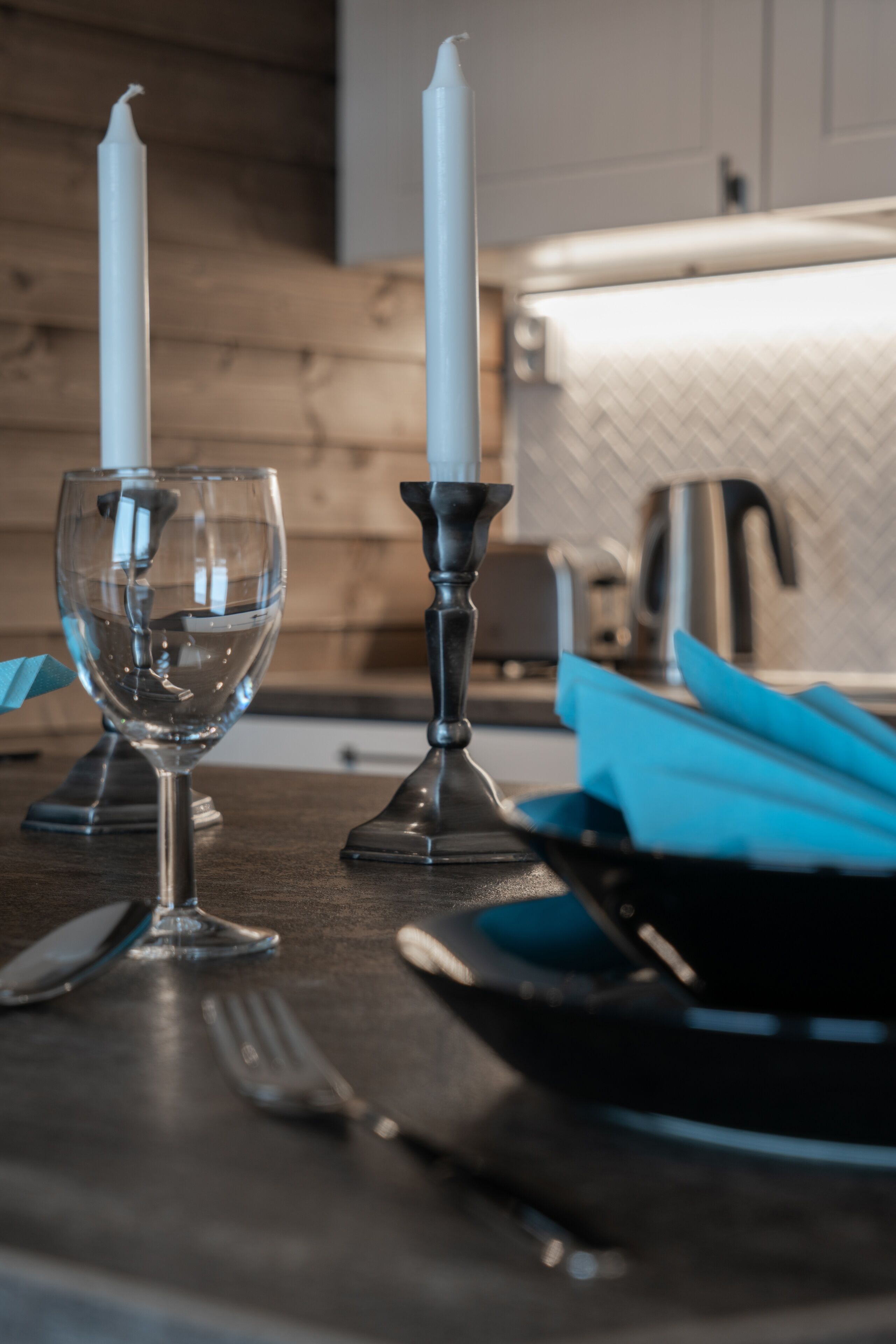 A table set with a wine glass, a candle, and cutlery.