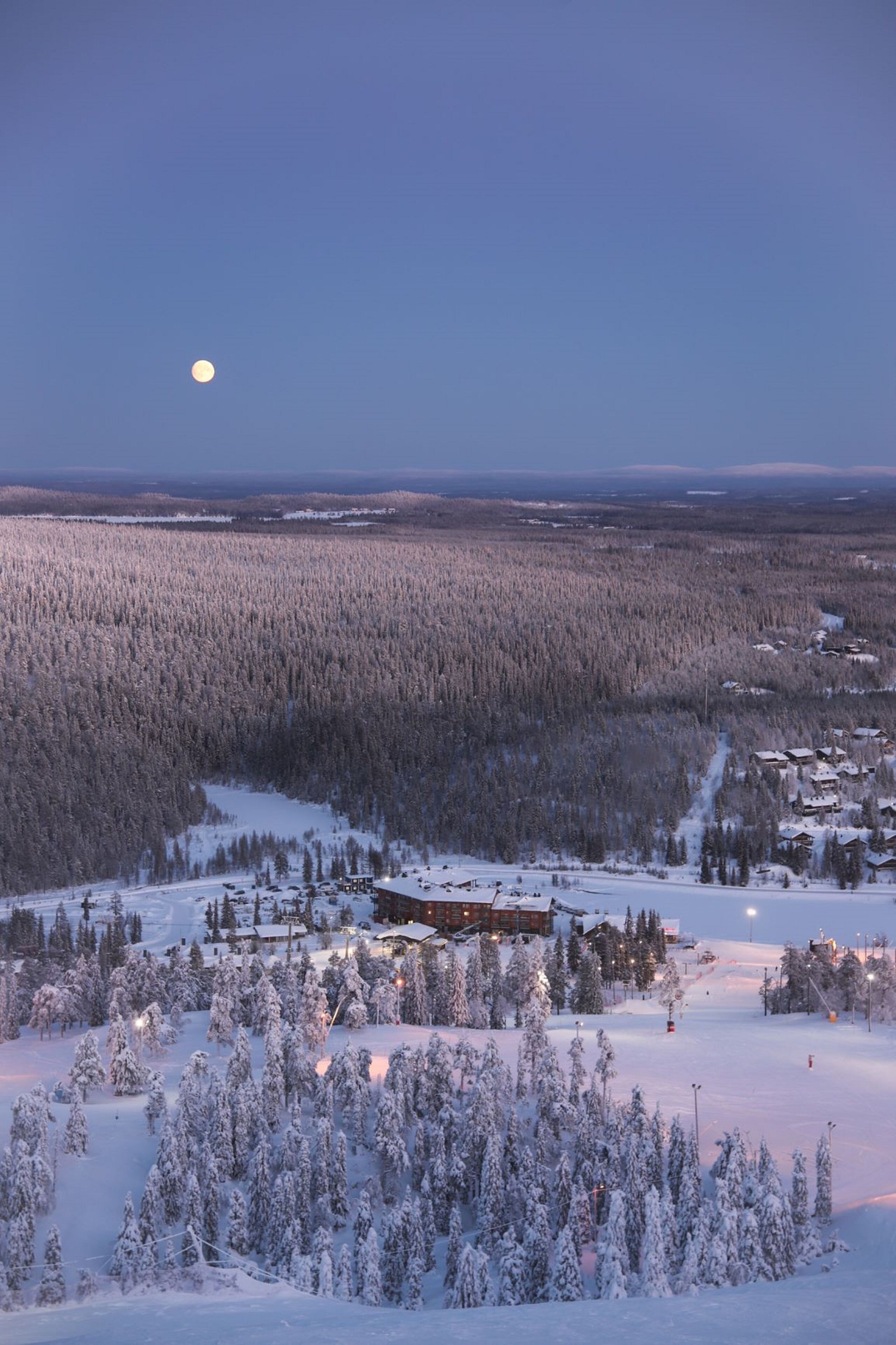 A snow-covered landscape with a lodge and a ski slope.