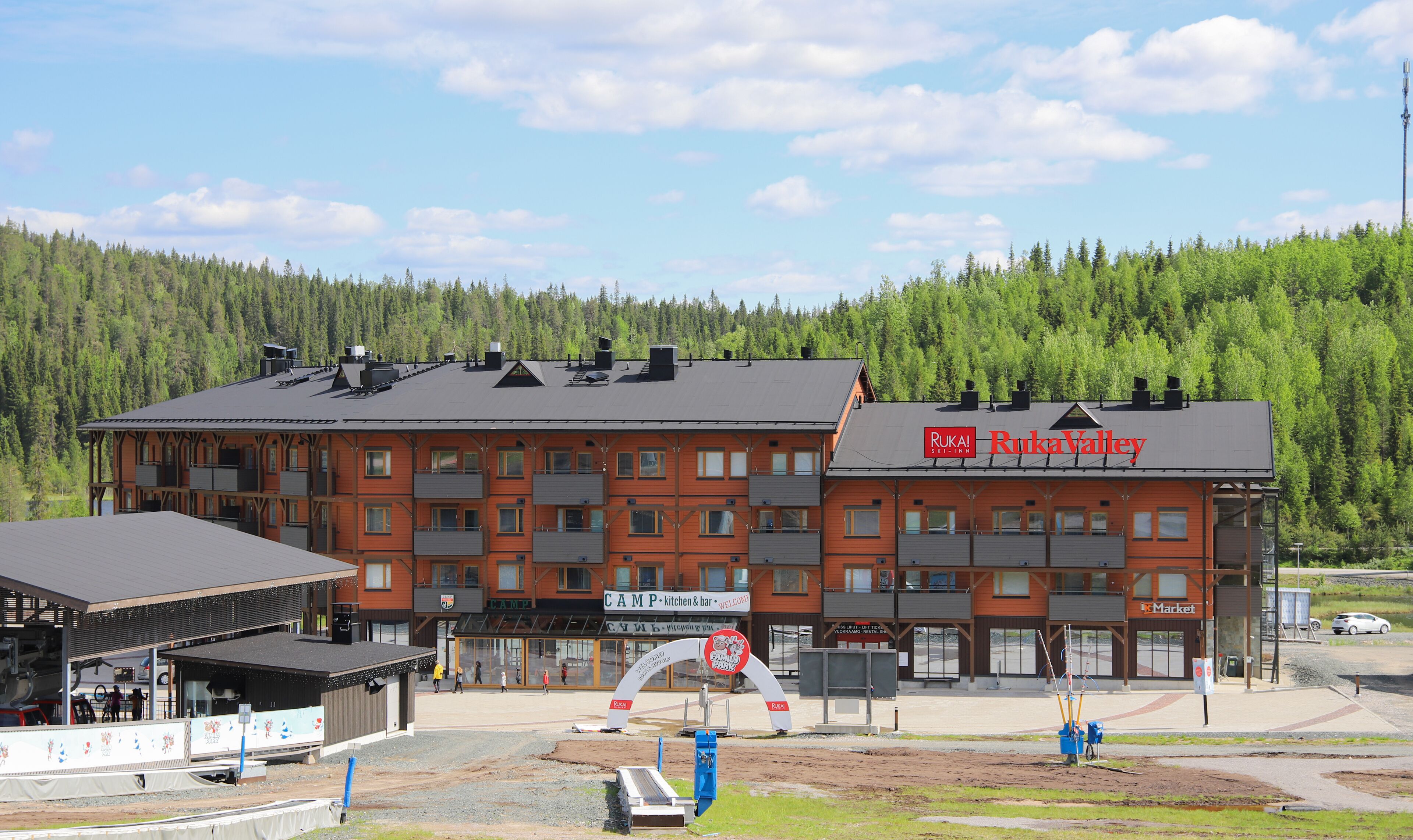 A multi-story hotel with a ski lift in the foreground, surrounded by a forested area.