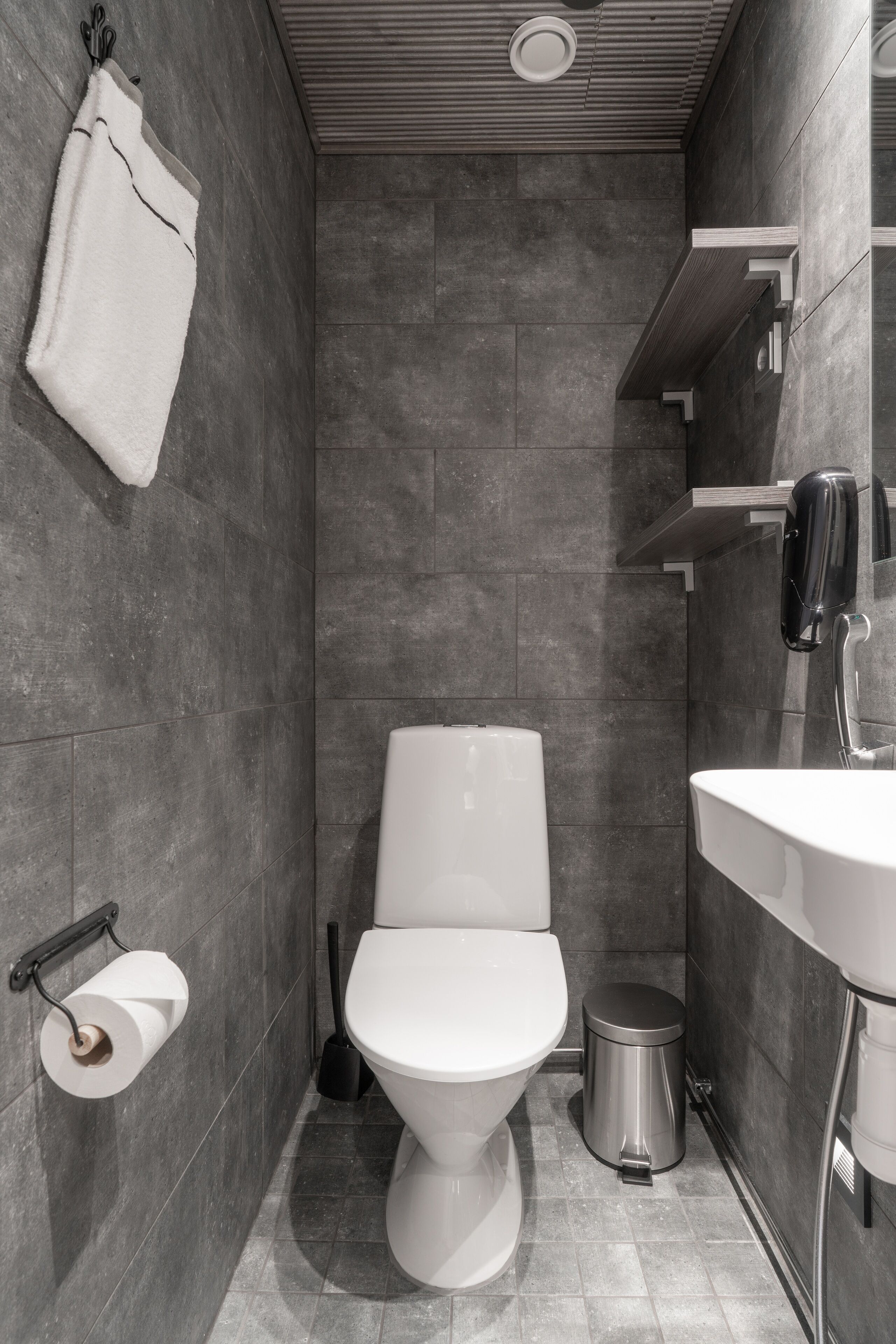 Ein modernes Badezimmer mit Toilette, Waschbecken und Handtuchhalter.