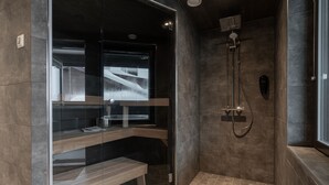 A modern bathroom with a glass-enclosed shower, a bench, and a built-in sink. - Ski-Inn RukaValley (Kuusamo)