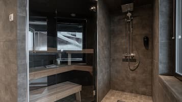 Shower area features a glass door, handheld showerhead, and wall-mounted faucet, with a bench for comfort.