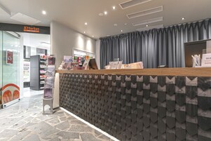 A reception desk with a patterned wall, a counter with informational brochures, and a store in the background.