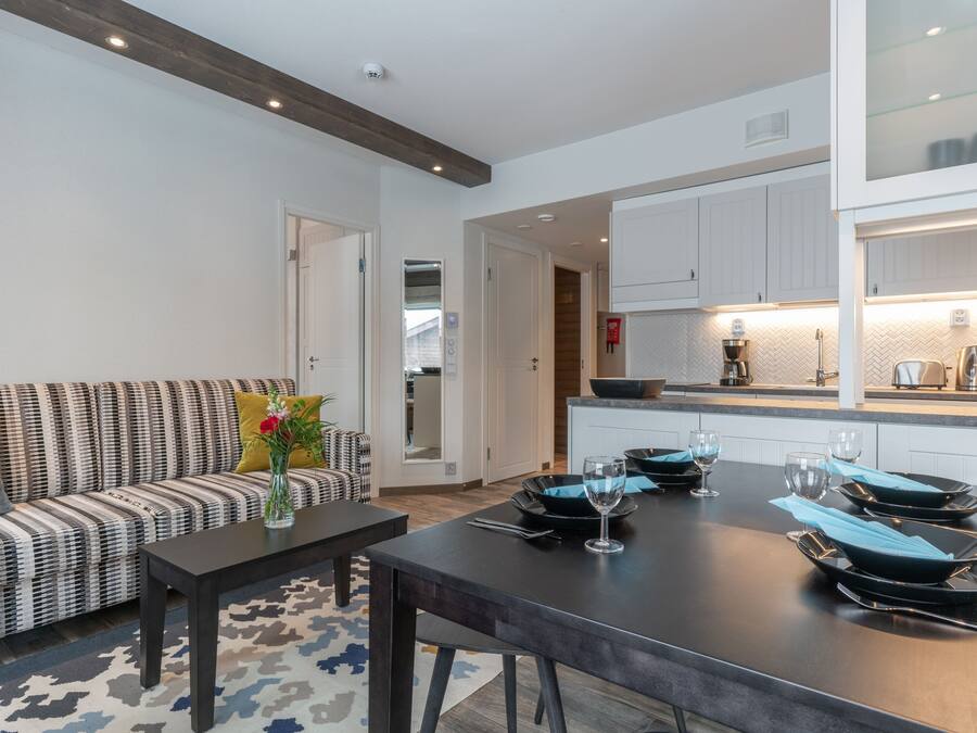 A modern kitchen with white cabinets, a black countertop, and a dining area with a black table and chairs.