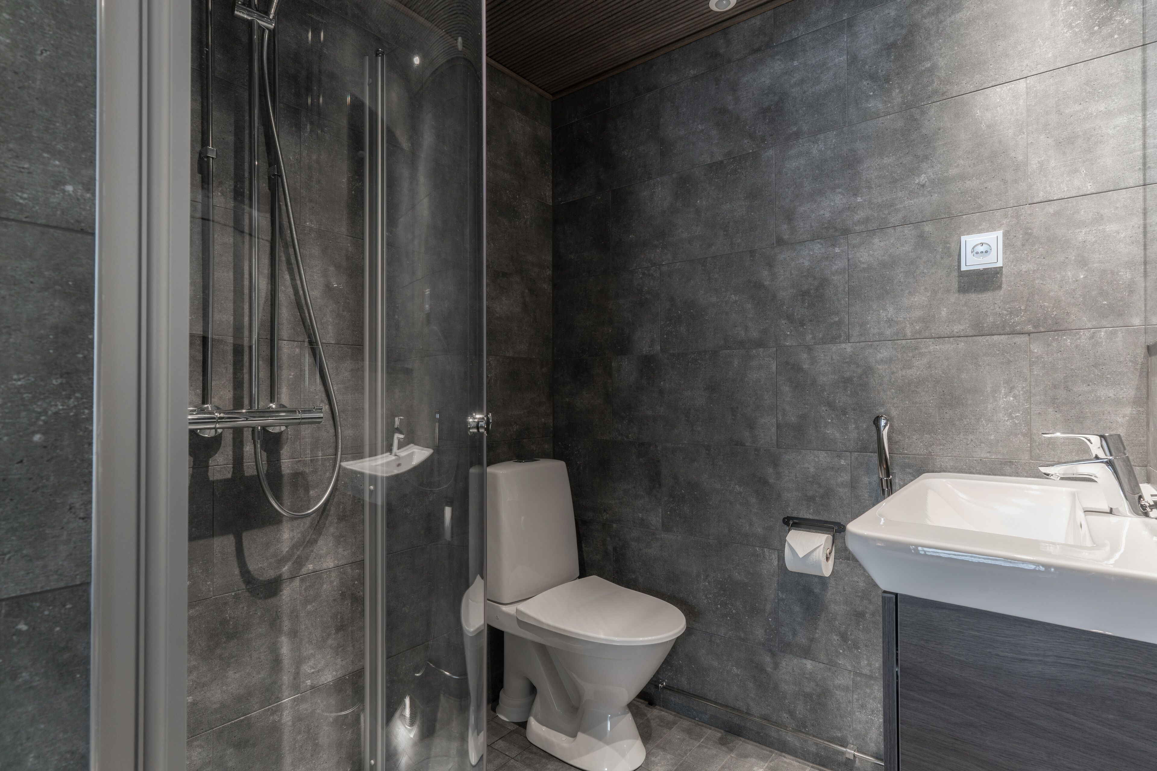 Une salle de bain moderne dotée d’une douche à parois de verre, de toilettes et d’un lavabo.