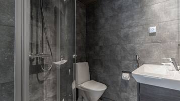 Une salle de bain moderne dotée d’une douche à parois de verre, de toilettes et d’un lavabo.
