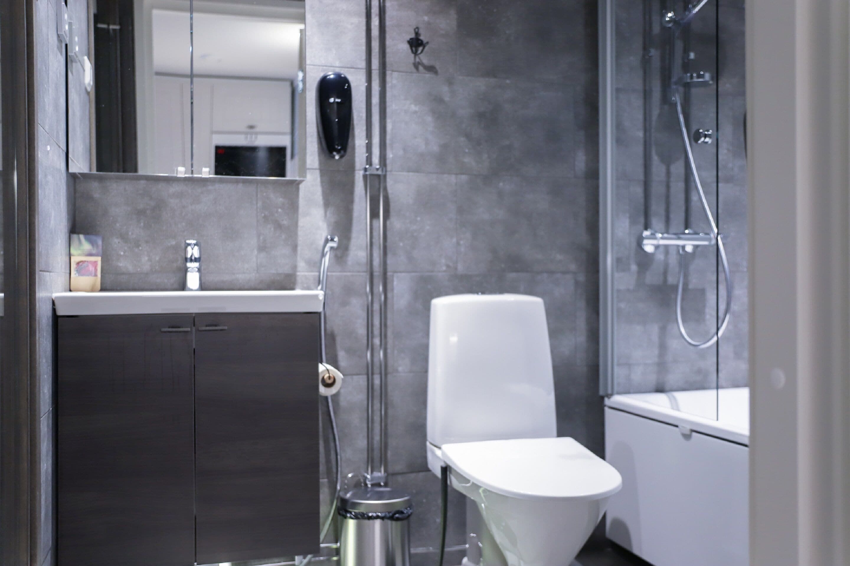 A modern bathroom with a toilet, a shower, and a sink.