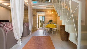 Un intérieur moderne avec un escalier, un coin repas et une vue sur l’extérieur.