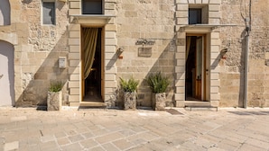 Un bâtiment en pierre doté de deux portes, chacune étant munie d’un rideau. Des plantes en pot sont placées devant les portes.